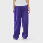 A model wears bright purple corduroy pants from GANNI featuring a cool, baggy fit - back view.