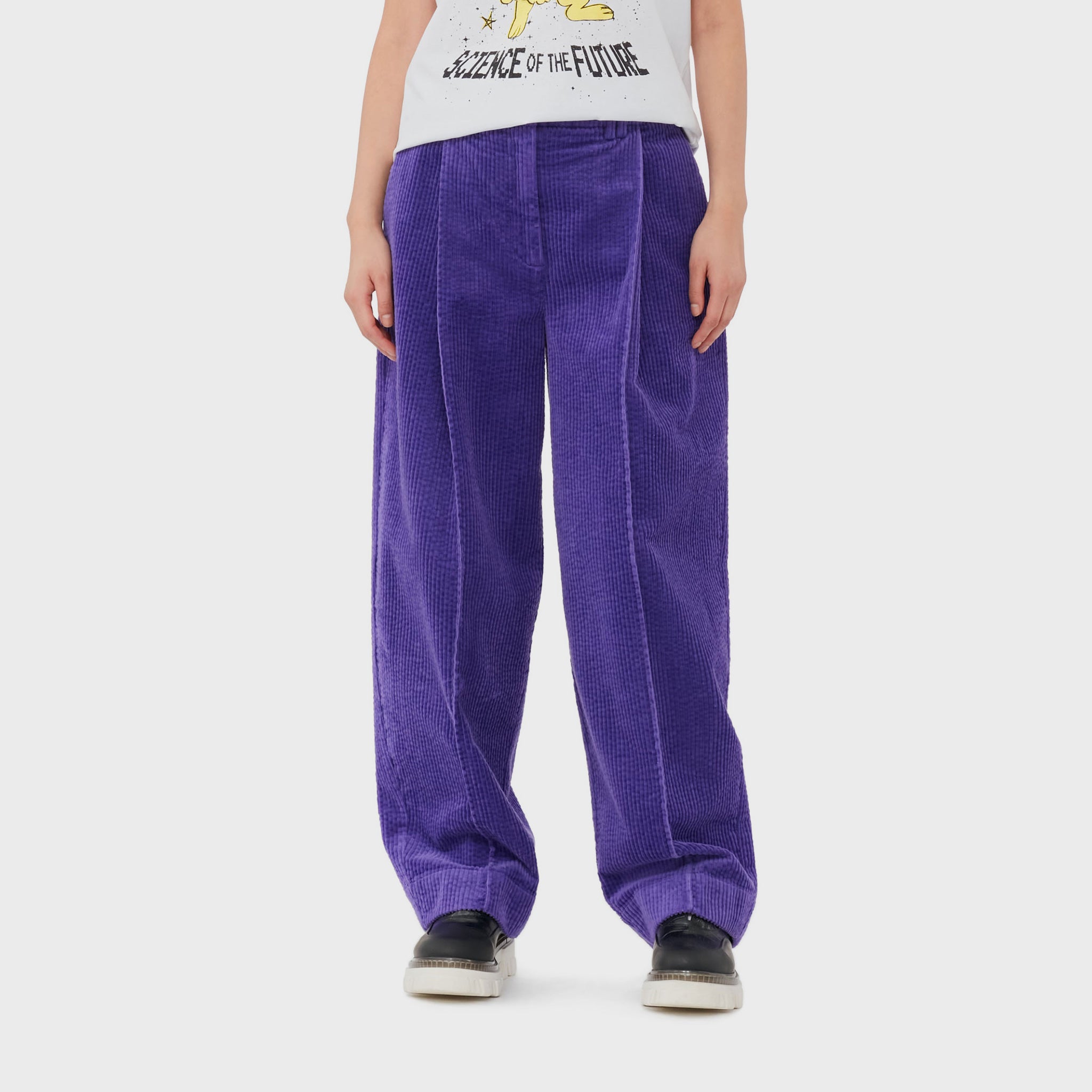 A model wears bright purple corduroy pants from GANNI featuring a cool, baggy fit.