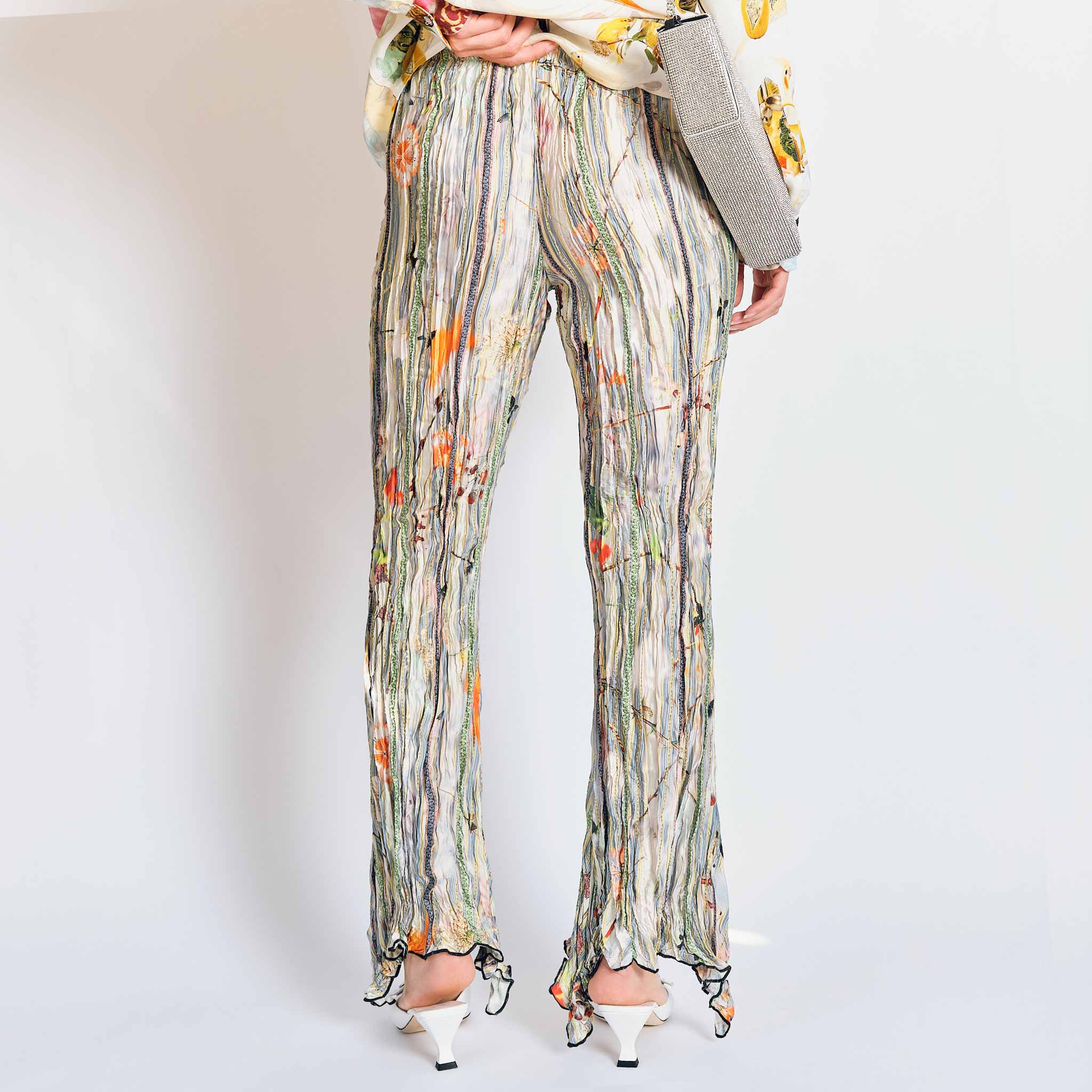 A model wears the pleated Dahlia trousers with light green, grey graphic floral print - back view.
