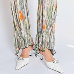 A model wears the pleated Dahlia trousers with light green, grey graphic floral print - hem detail.