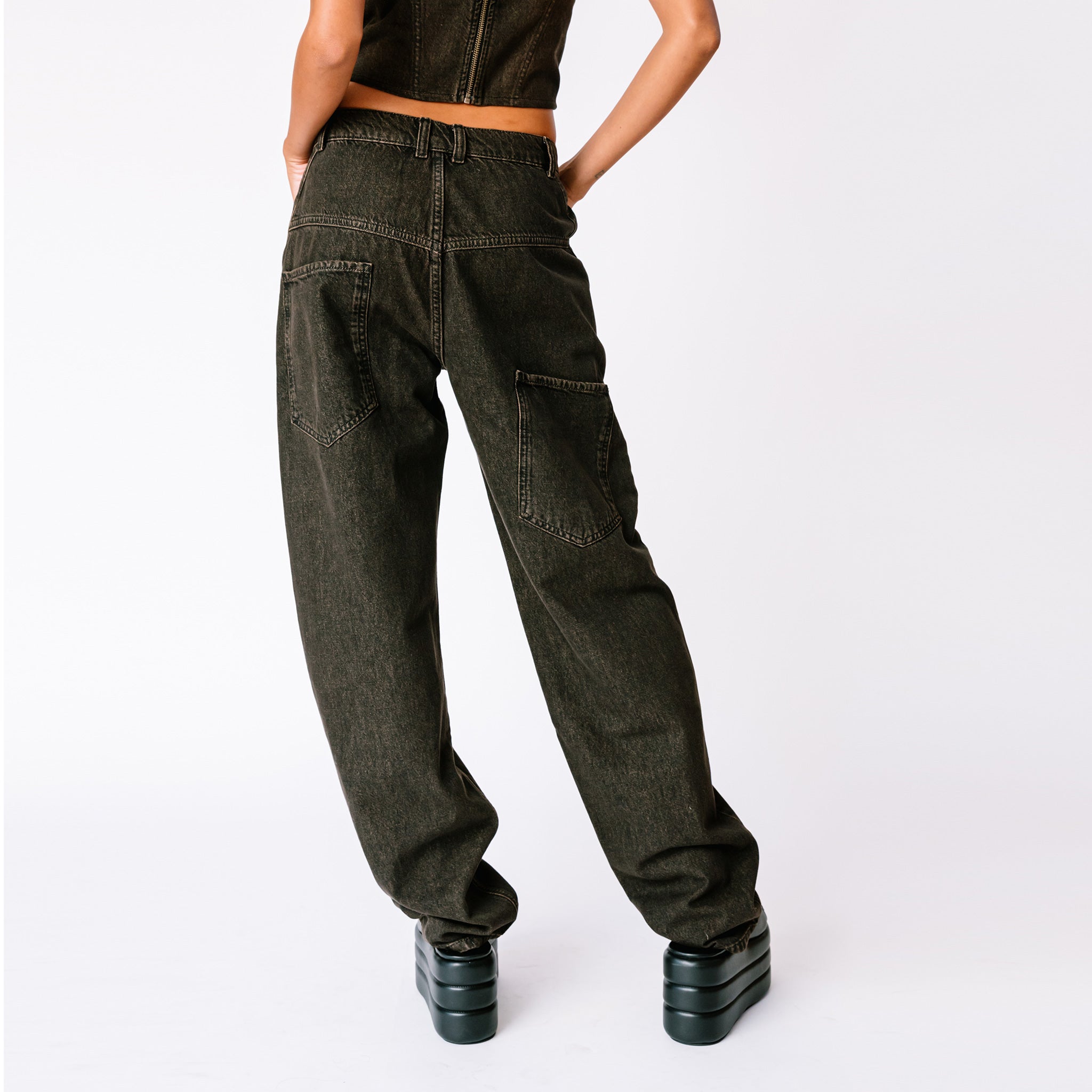 A model wears the baggy faded black Echo Jeans by Miaou, paired with the matching strappy Kiko corset, back view.