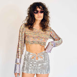 A model wears the cropped, long-sleeved, multicolored knit Eteri sweater with purple metallic dipped sleeves - front view.