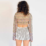A model wears the cropped, long-sleeved, multicolored knit Eteri sweater with purple metallic dipped sleeves - back view.