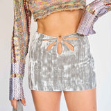 A model wears the Flower Mini Skirt - a silver velvet mini skirt with multiple cutouts in the shape of a flower - detail view.