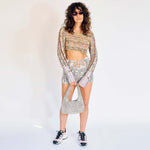A model wears the Flower Mini Skirt - a silver velvet mini skirt with multiple cutouts in the shape of a flower - full outfit view.