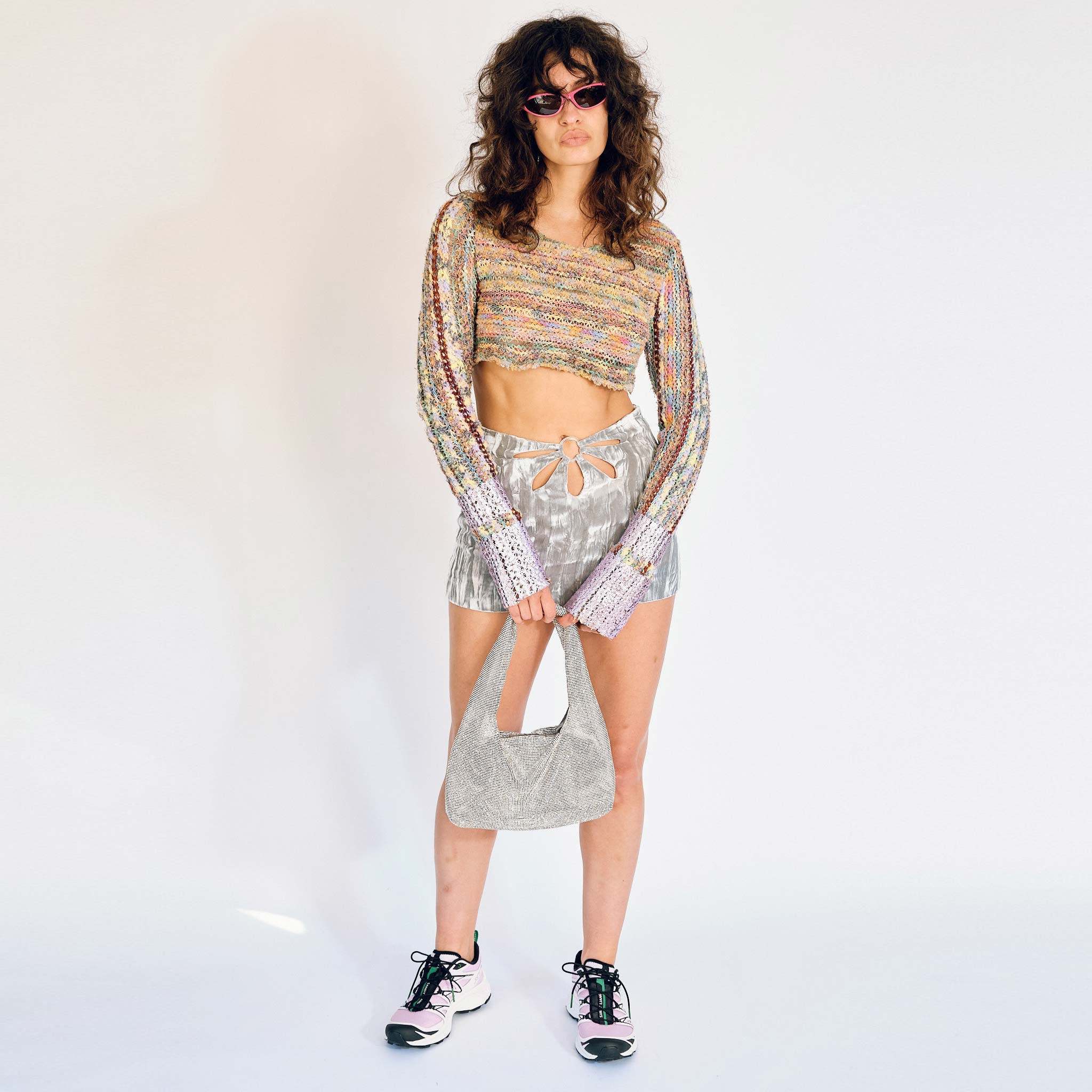 A model wears the Flower Mini Skirt - a silver velvet mini skirt with multiple cutouts in the shape of a flower - full outfit view.