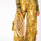 A model holds the wooden beaded Fruit Tote by Not Impressed against her leg.
