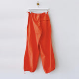 Back hanging photo of the High Rise Parachute Cargo Pants - Orange.