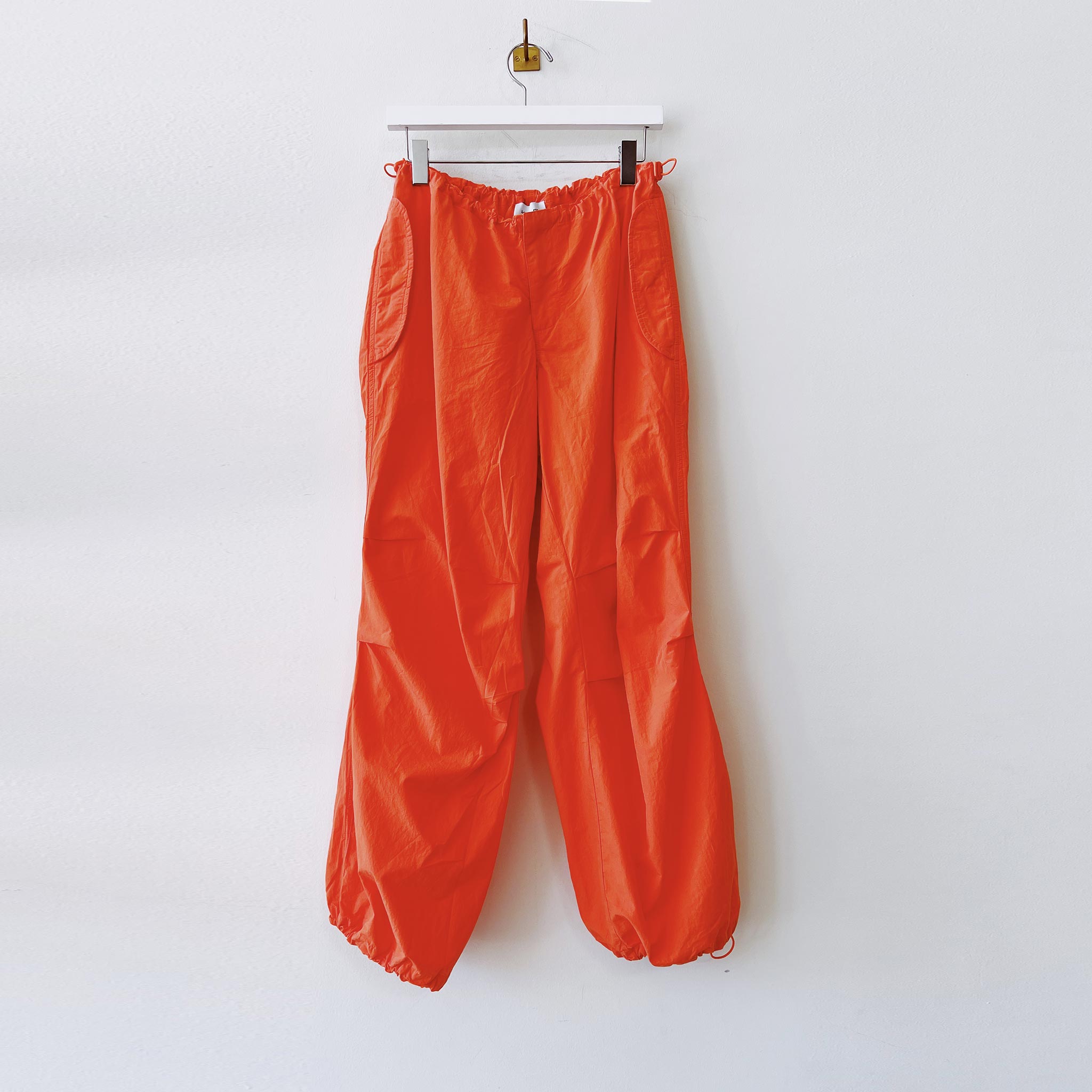 Hanging photo of the High Rise Parachute Cargo Pants - Orange. 