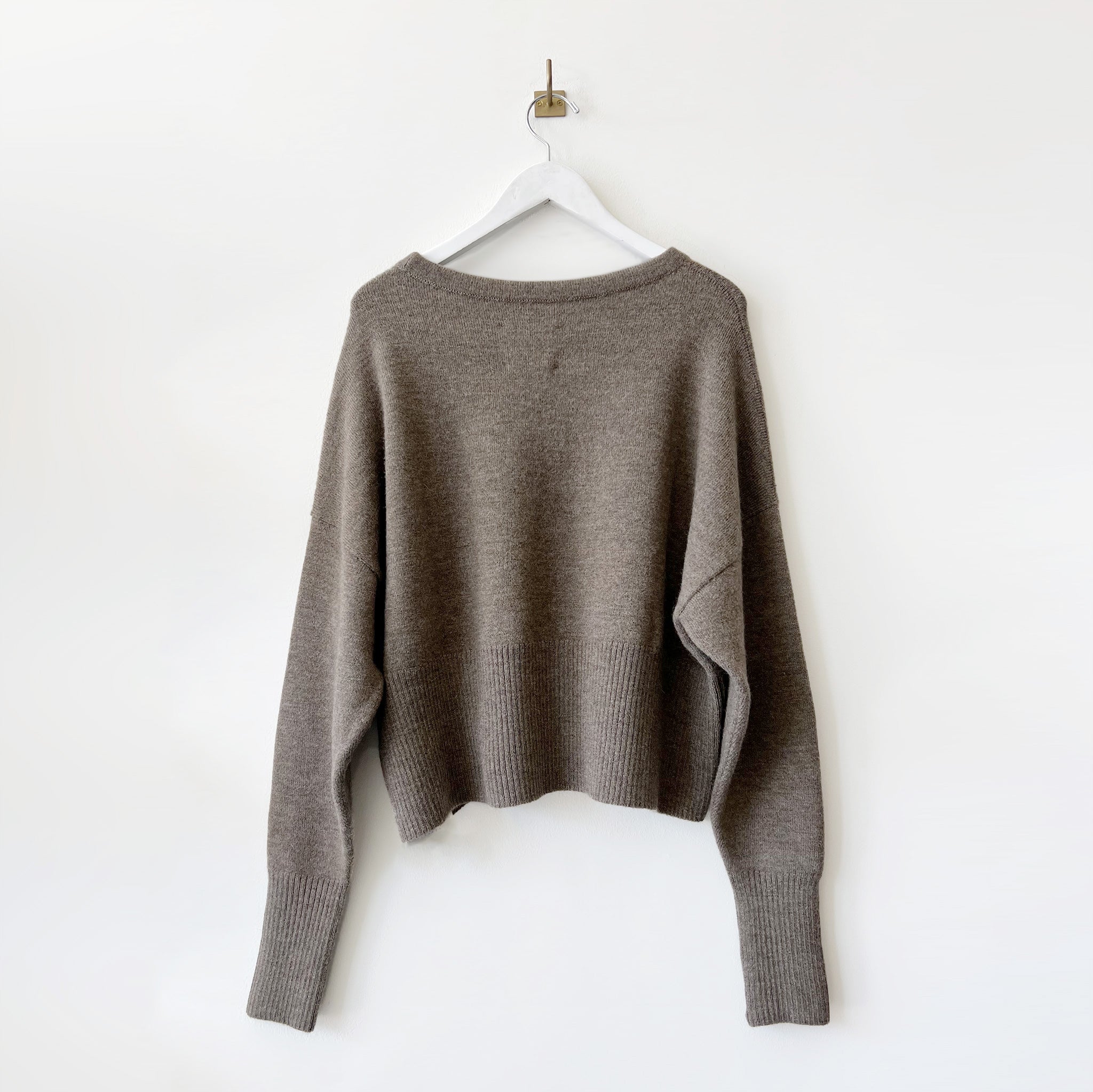 A boxy crewneck sweater with long loose sleeves and a cropped waist - back side.