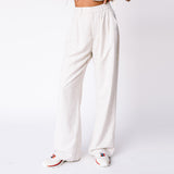 A model wears the high rise linen trousers by Misc Etc, paired with the Tie Top and sneakers, front view.