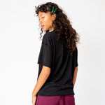A model wears the Inside Out Tee in jet black, paired with merlot colored sweat shorts - back view.