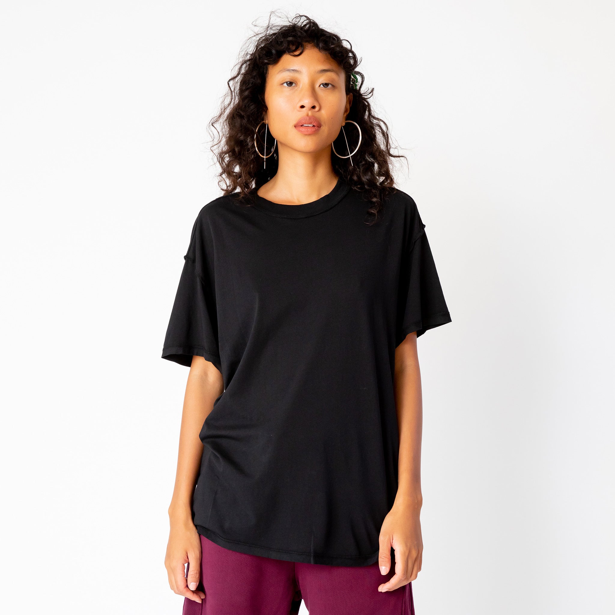 A model wears the Inside Out Tee in jet black, paired with merlot colored sweat shorts - front view.
