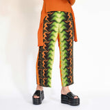 A model wears the green orange and black graphic printed pleated pant - front view.