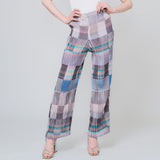 Pleated high waist trousers with a gridded graphic pattern in greys, whites, and blues - model with her hands on her waist