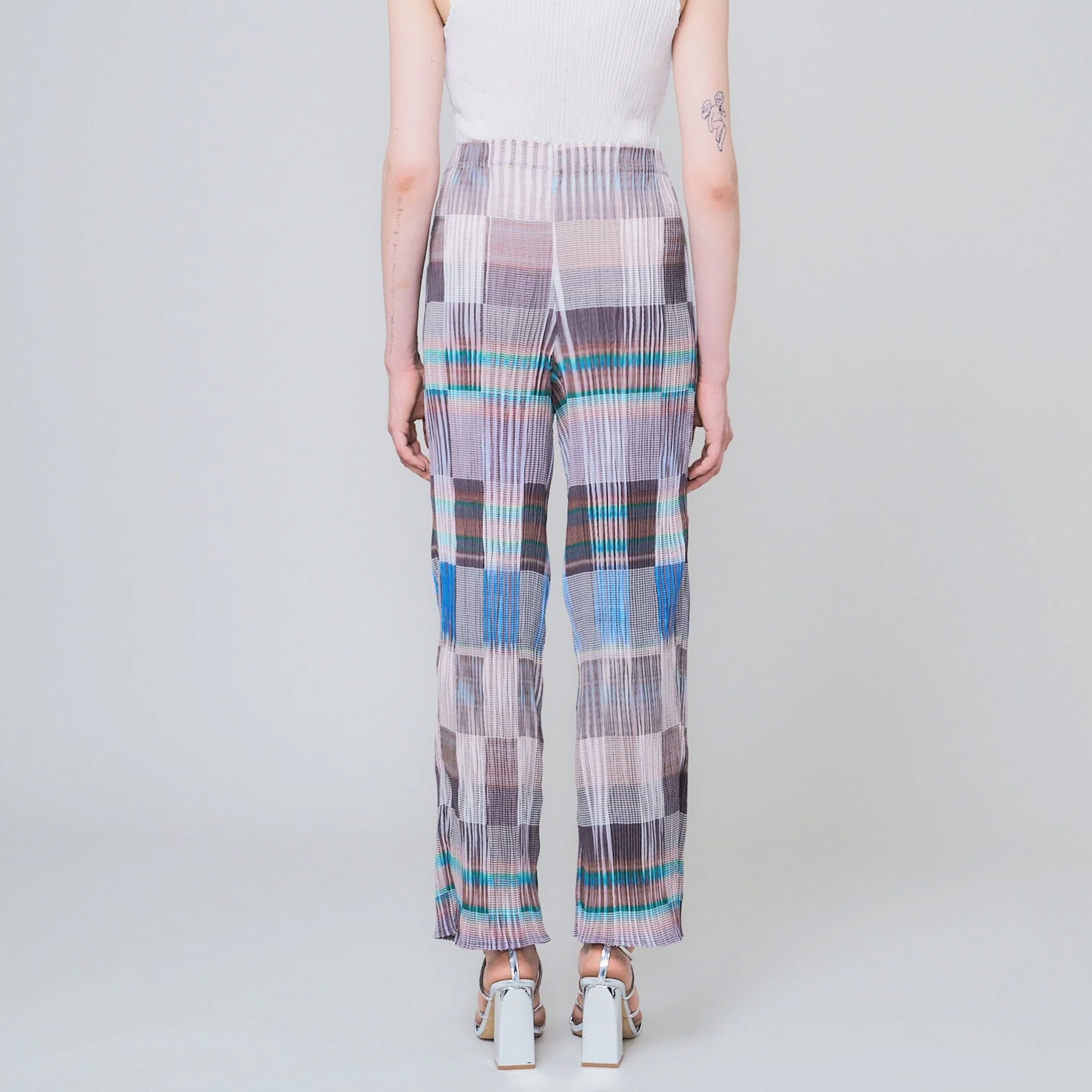 Pleated high waist trousers with a gridded graphic pattern in greys, whites, and blues - back view on model.