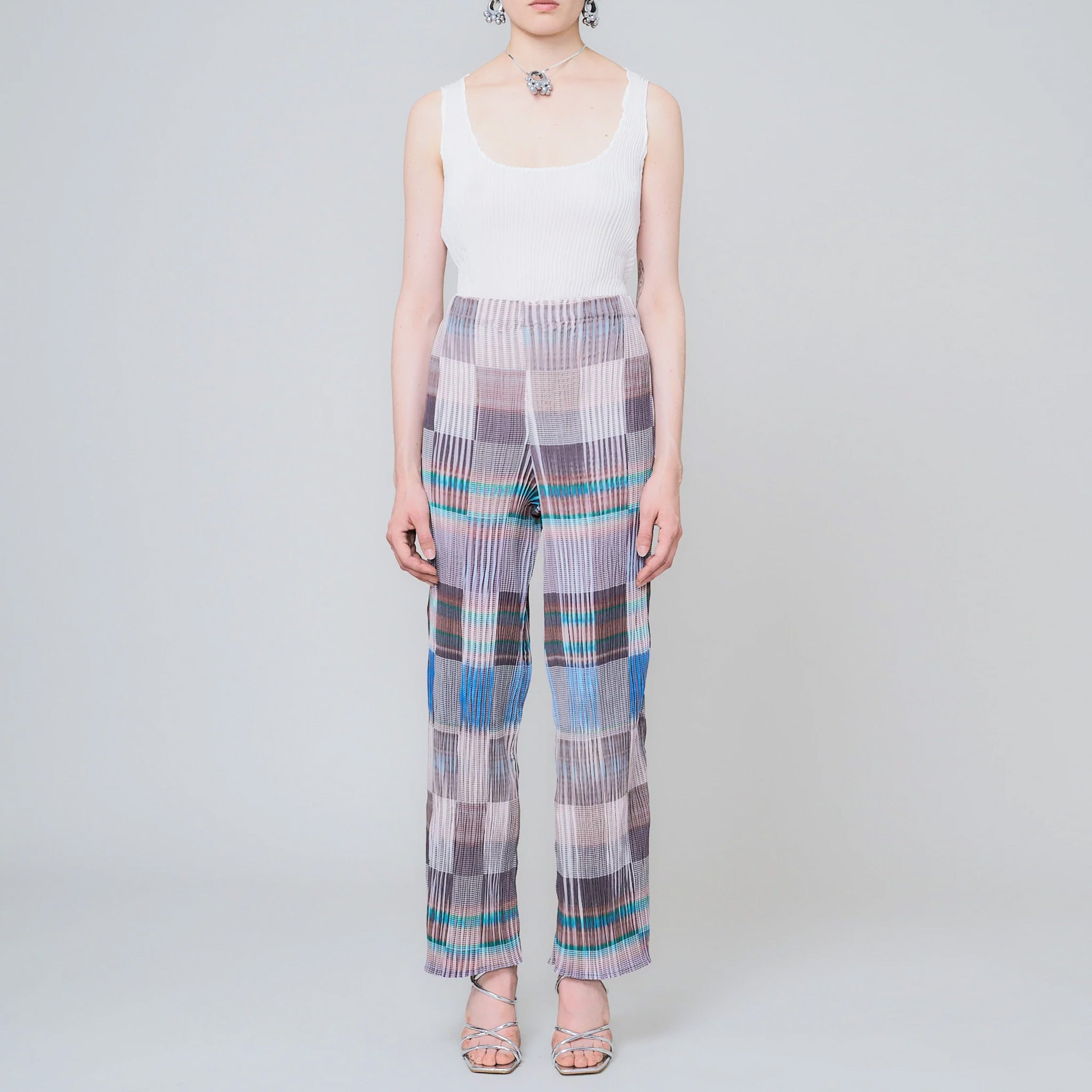 Pleated high waist trousers with a gridded graphic pattern in greys, whites, and blues - front view.
