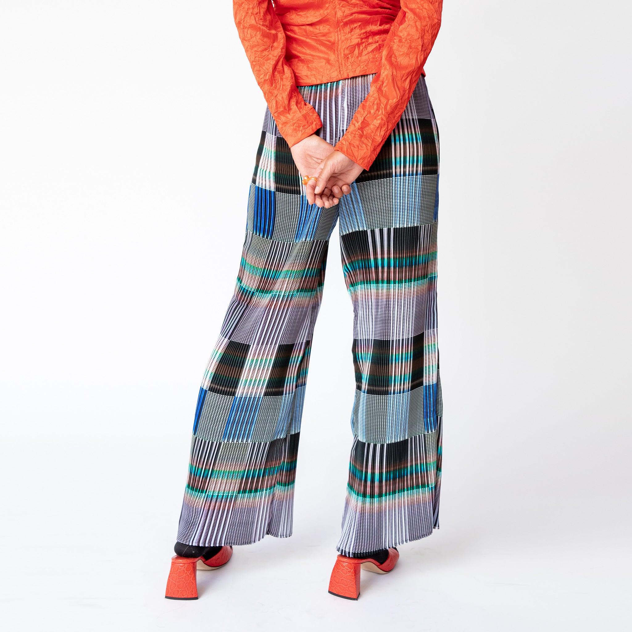 Rear view of the Julie Heuer pleated Jack Trousers in a gridded print pattern as worn with a vibrant red blouse.