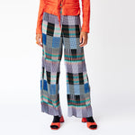 Front detail view of the Julie Heuer pleated Jack Trousers in a gridded print pattern as worn with a vibrant red blouse.