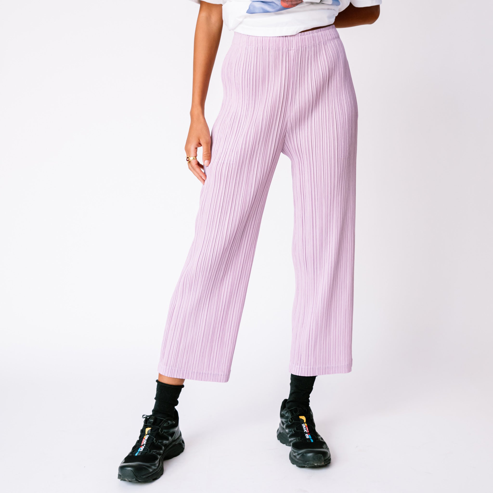 A model wears the Thicker Bottoms Pant in Pink Purple by Pleats Please, paired with black sneakers.