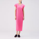 Full body photo of model wearing the Monthly Colors July S/S Dress - Bright Pink, a short sleeved full length pleated dress.