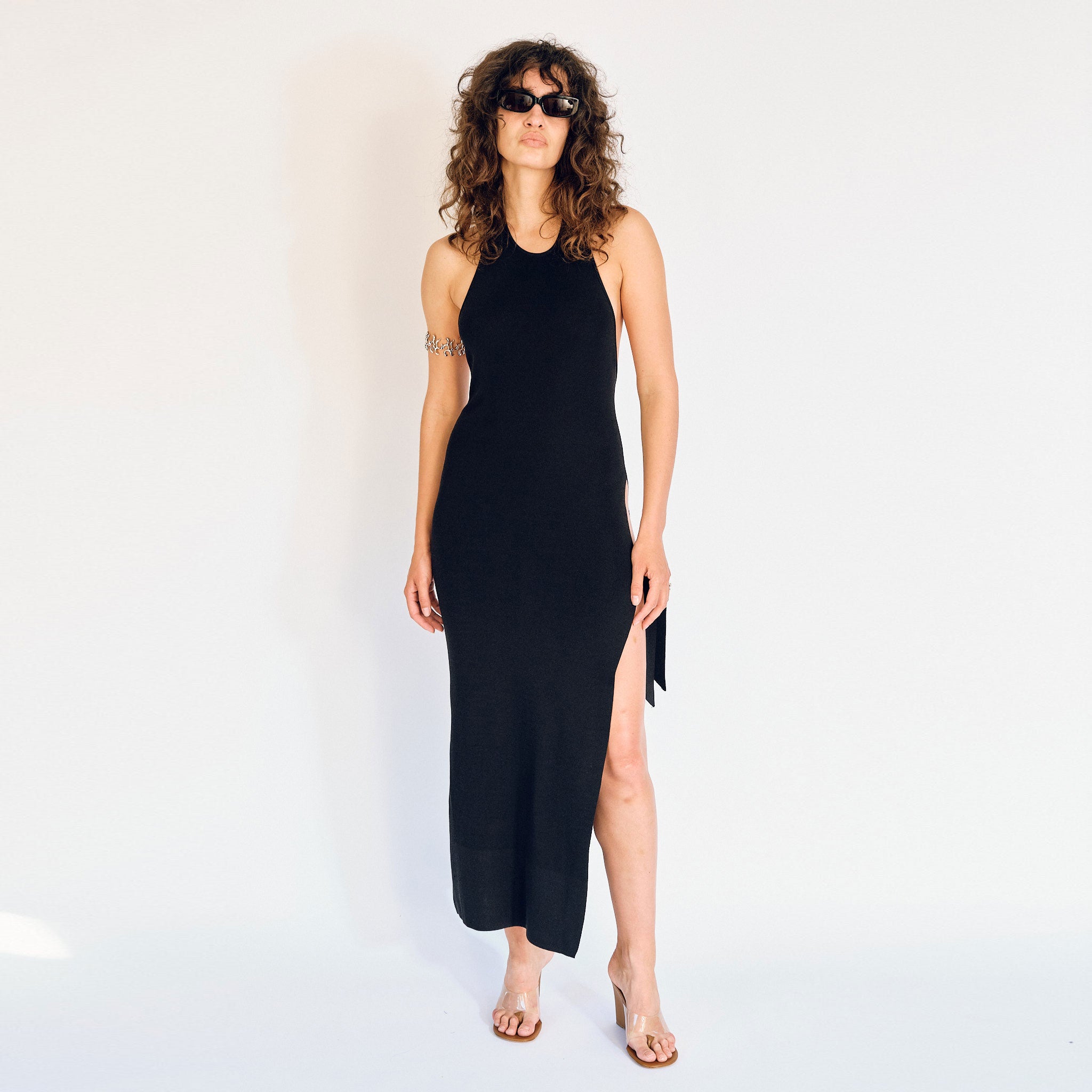 A model wears the Simon Miller Junjo tank style dress in black, with high side slits along the left leg - front view.