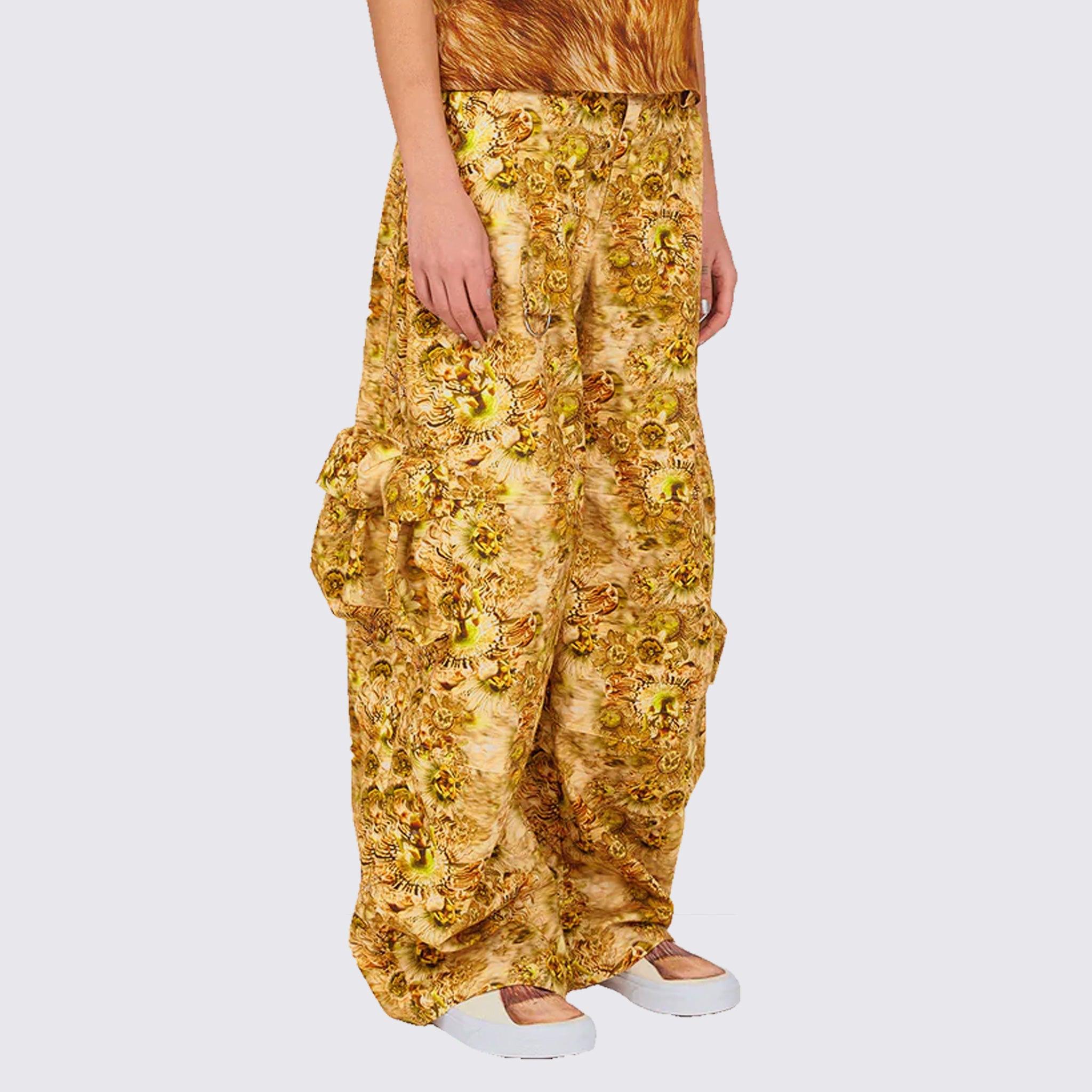A model wears the gold and brown graphic printed Lawn Cargo Pant featuring various large pockets and a zip fly, angled view.
