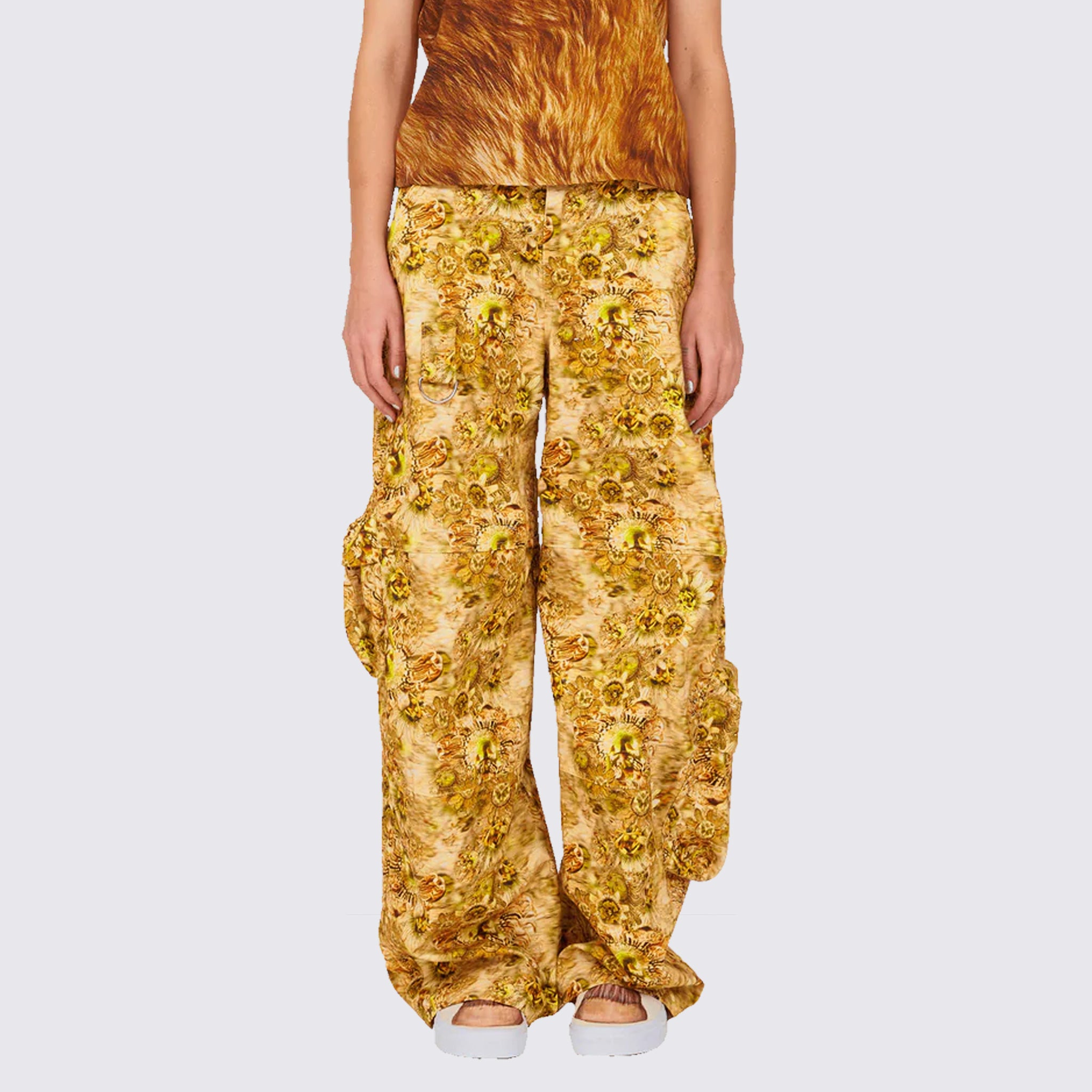 A model wears the gold and brown graphic printed Lawn Cargo Pant featuring various large pockets and a zip fly, front view.