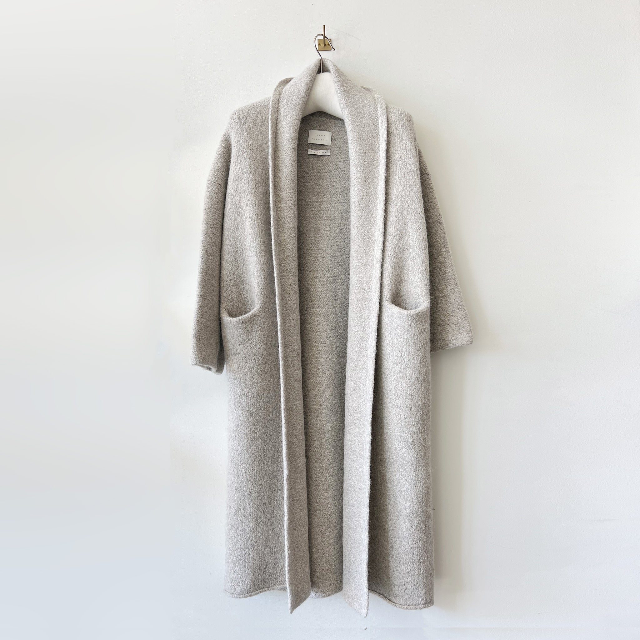 Long light grey cardigan-like coat with a shawl collar and slitted front pockets.