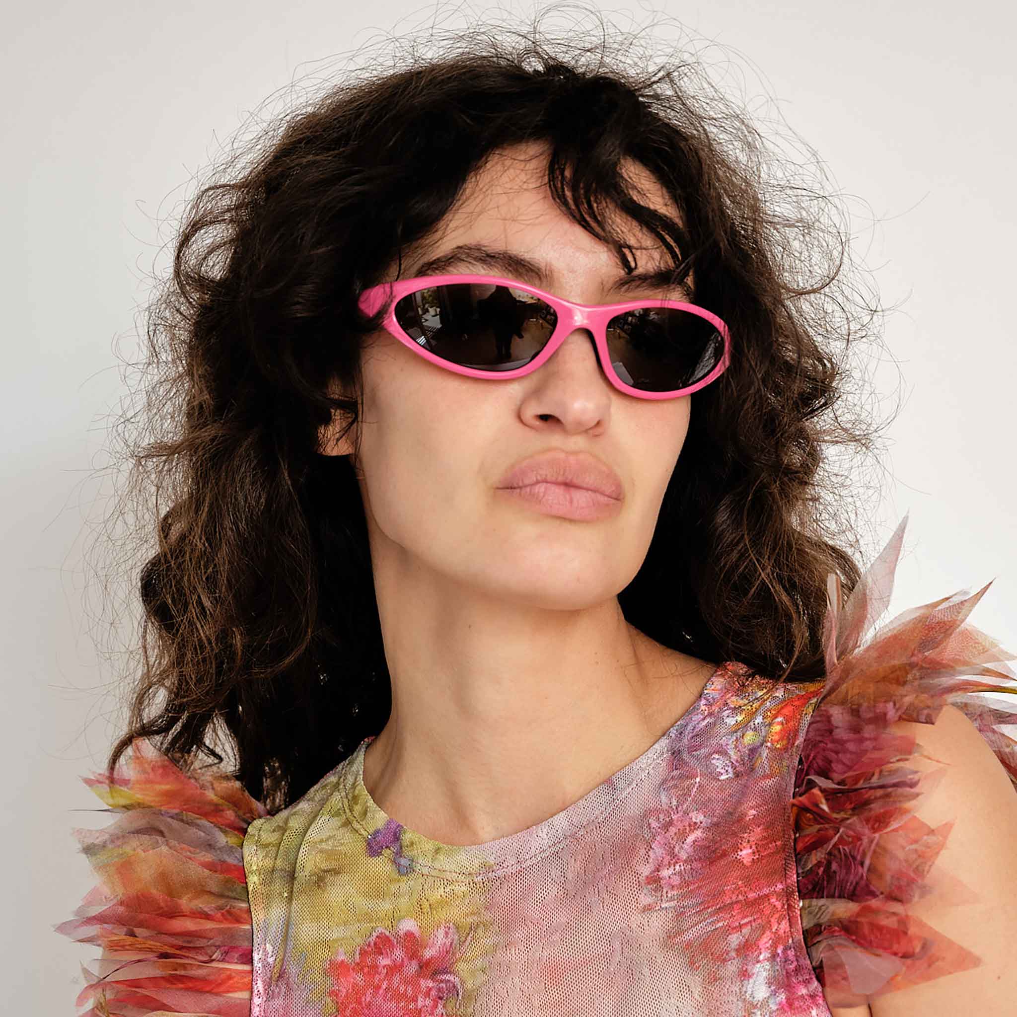 A model wears the Marine Serre x Vuarnet Injected Visionizer in Pink - a narrow and angled pair of sunglasses.
