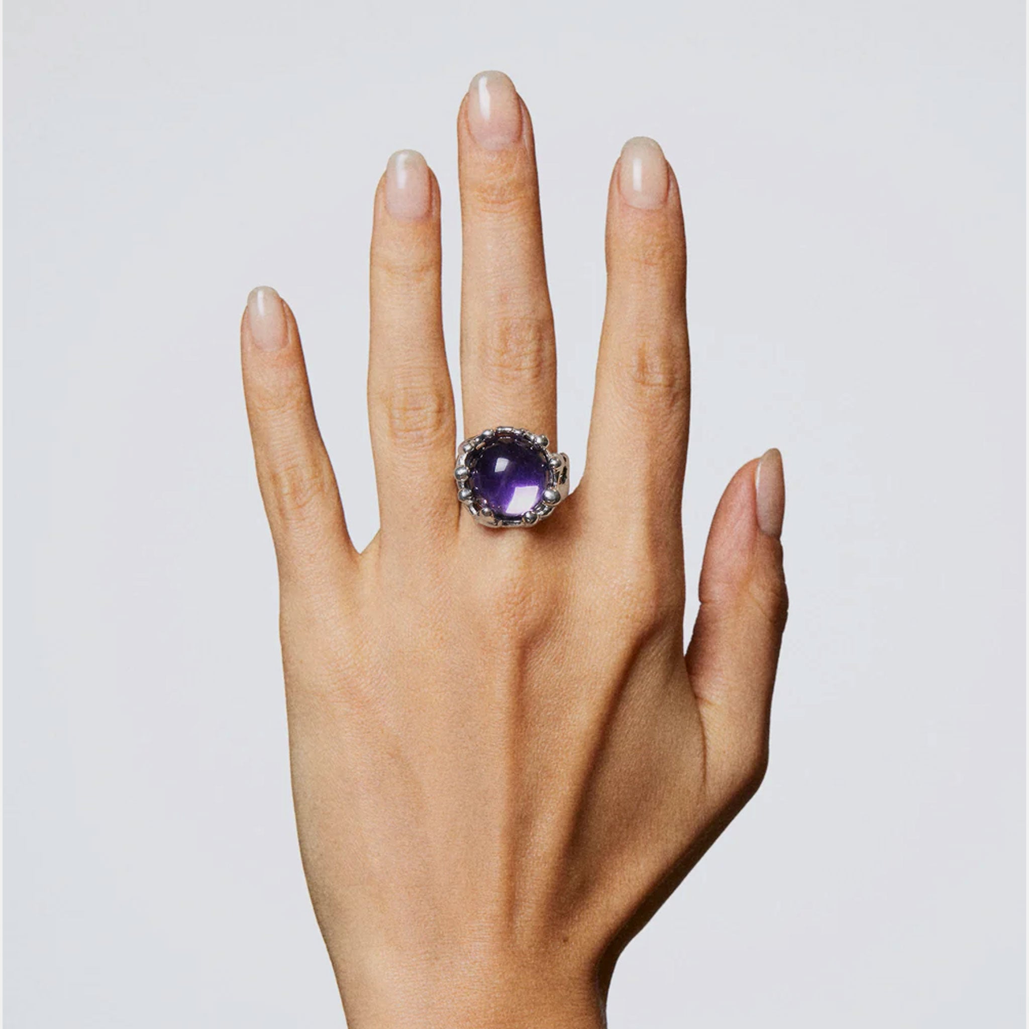 A model wears the circular silver-colored Magician Ring featuring a large round purple stone.