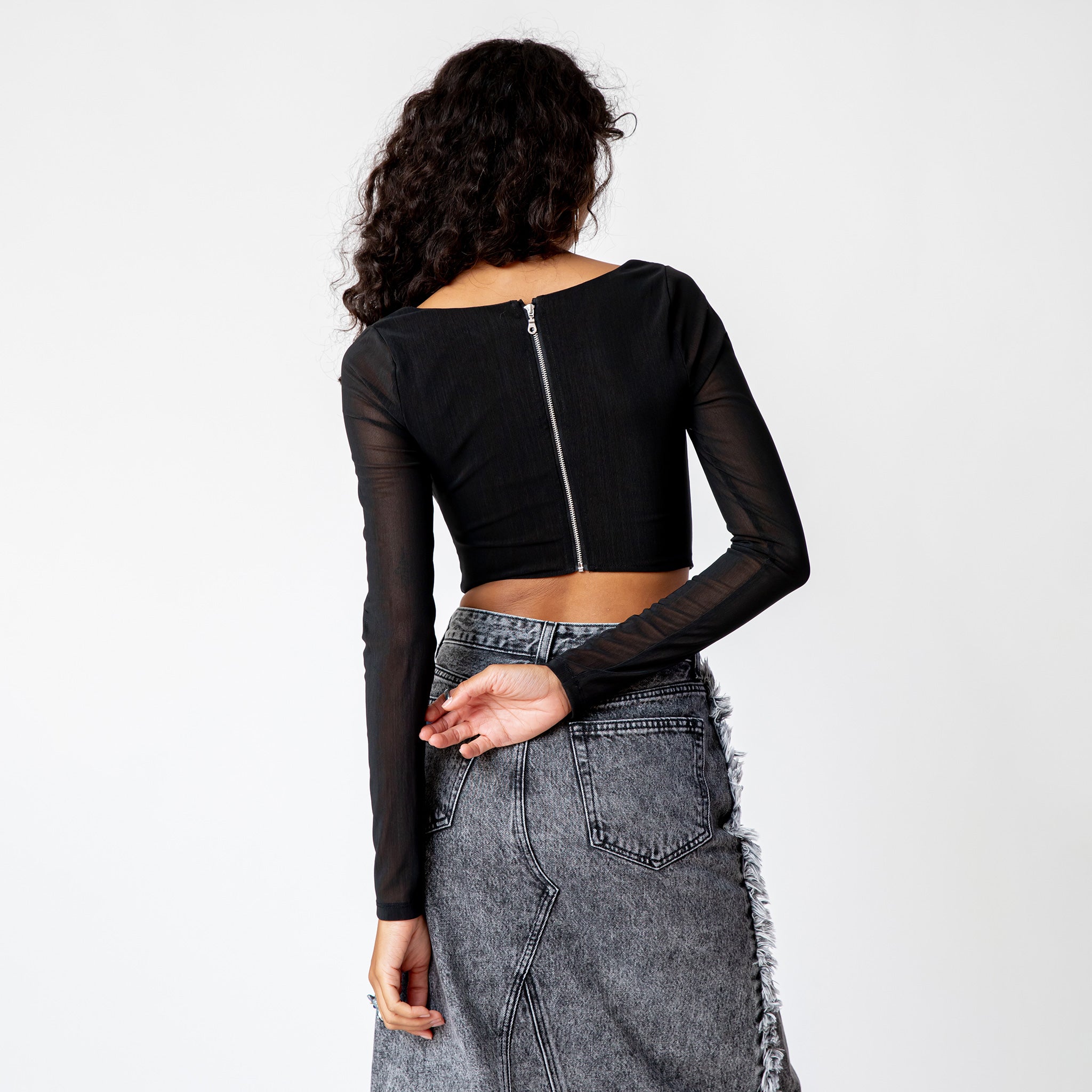 A model wears the long sleeved black mesh Maude Corset - back view.