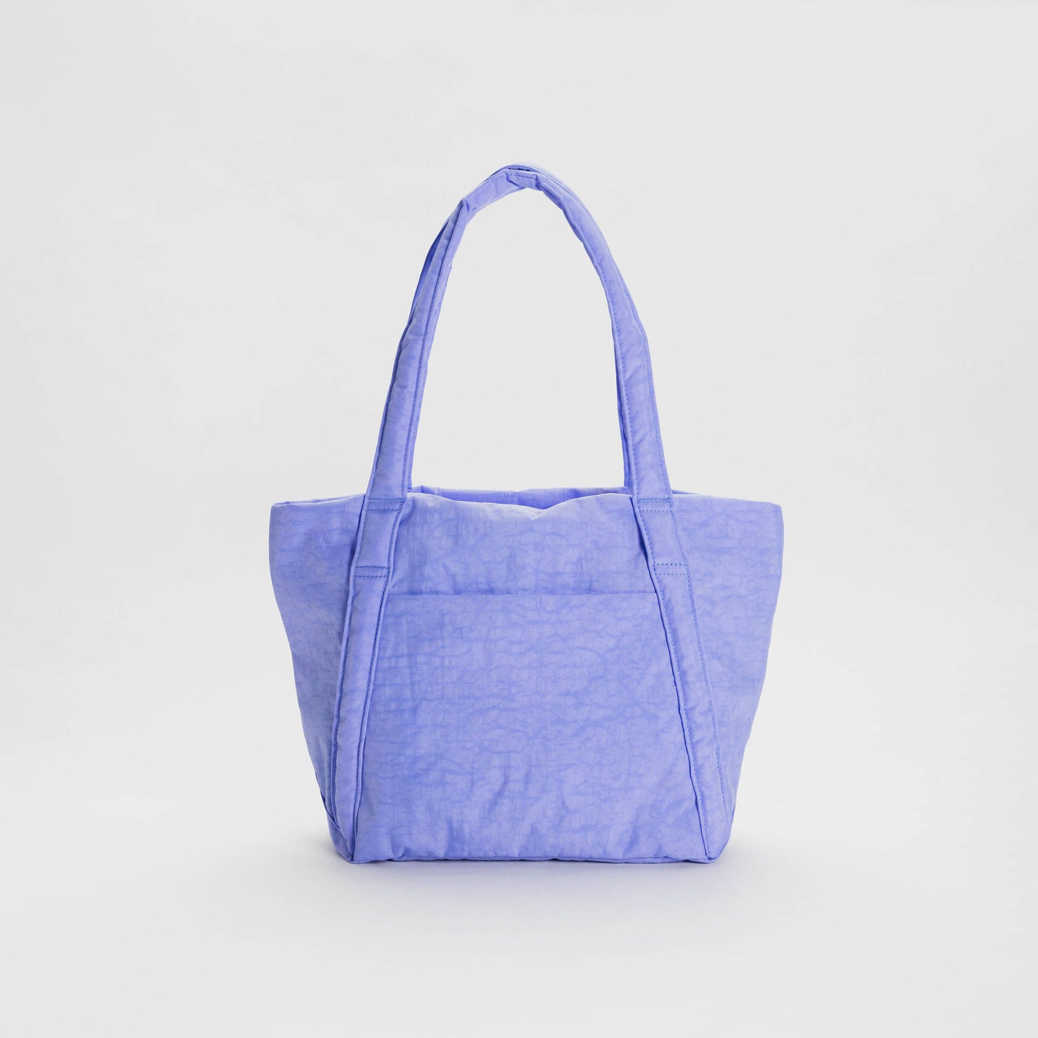 A periwinkle blue nylon shoulder tote with a puffy trapezoidal shape, shown standing up.