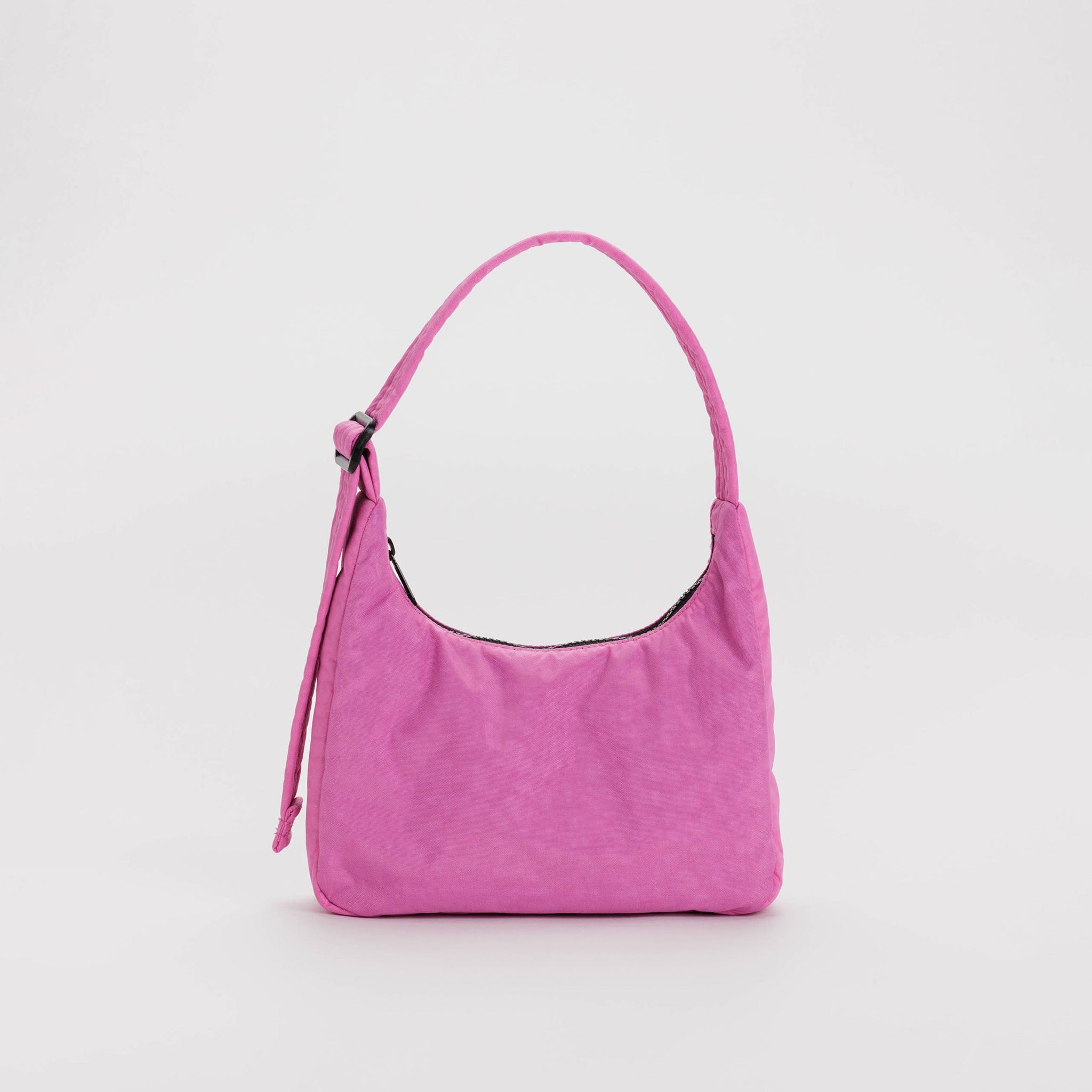 A pink nylon shoulder bag with a rectangular shape and top zipper, shown standing up.