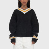 Half body photo of model wearing a oversized black v neck sweater with a white and yellow line around the neck and wrists.