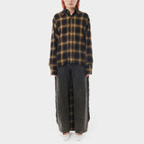 Front full body photo of model wearing a longsleeve flannel shirt with a black and yellow detail. 