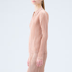 Close side half body photo of model wearing the pleated polo top in the color beige.