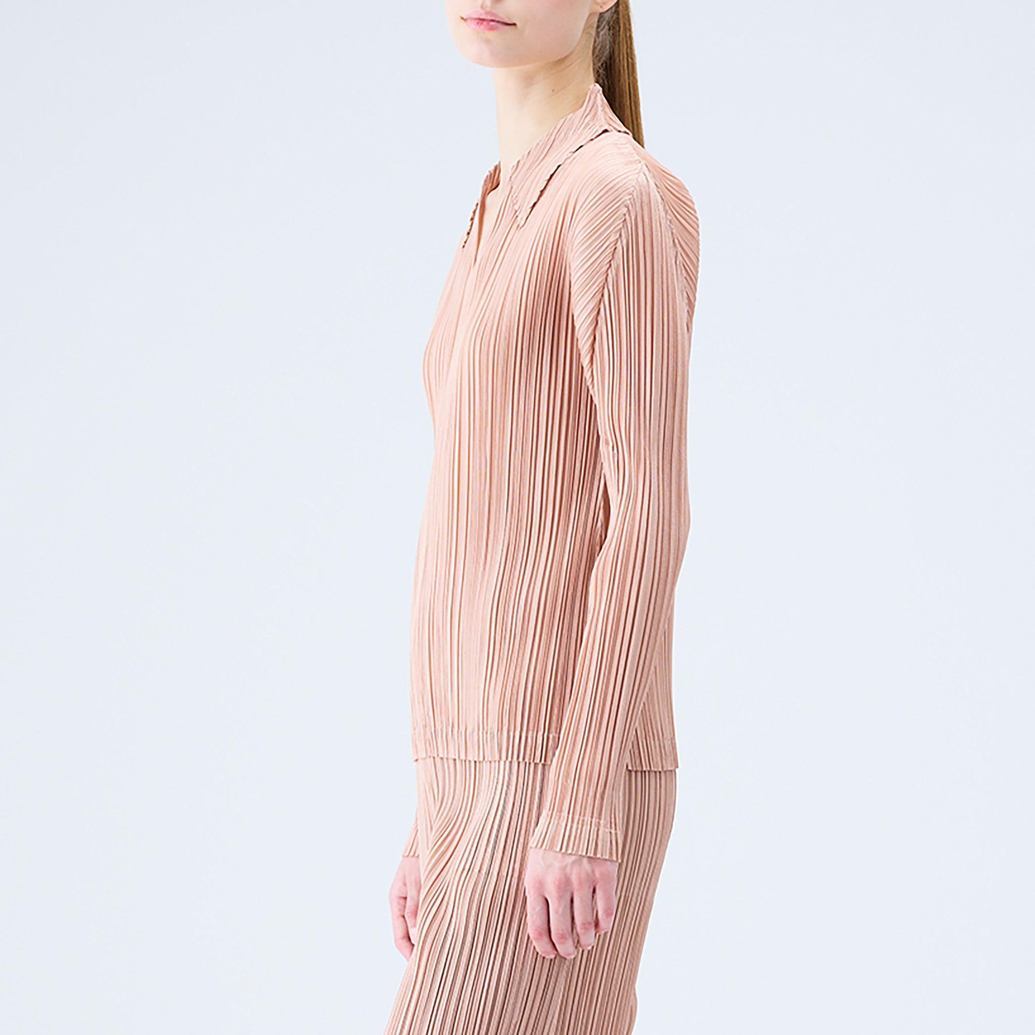 Close side half body photo of model wearing the pleated polo top in the color beige.
