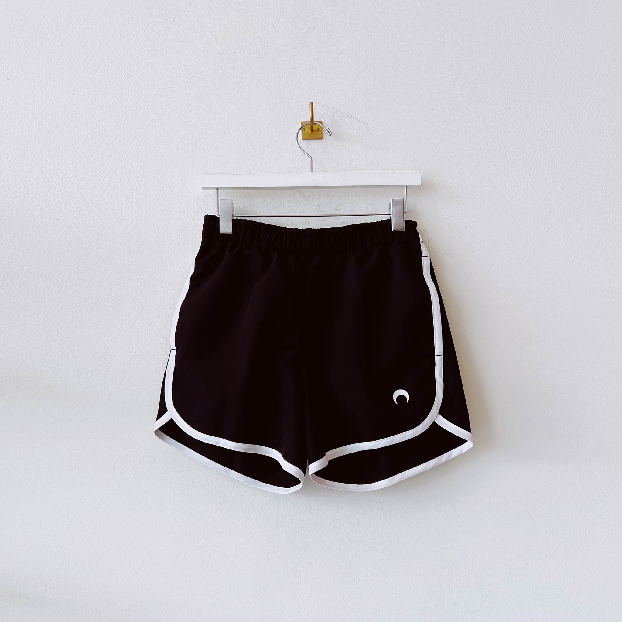 Vintage style running short in black with white piping and Marine Serre embroidered logo on front left thigh - front view.