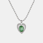 A silver-toned roughly shaped heart pendant necklace featuring a clear green stone - detailed image.