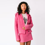 A model wears the chunky ribbed pink Paw Cardigan unbuttoned with the matching Barb ribbed skirt, front view.
