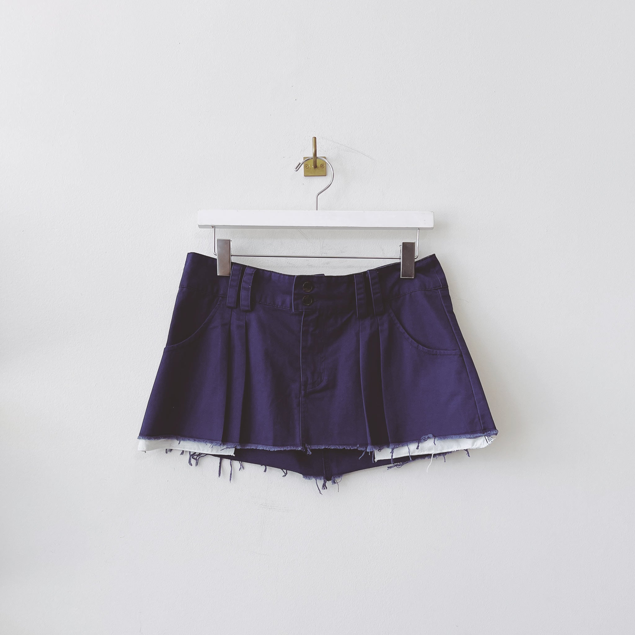 Flat hanging photo of the Pleated Low Rise Mini Skirt - Navy. 