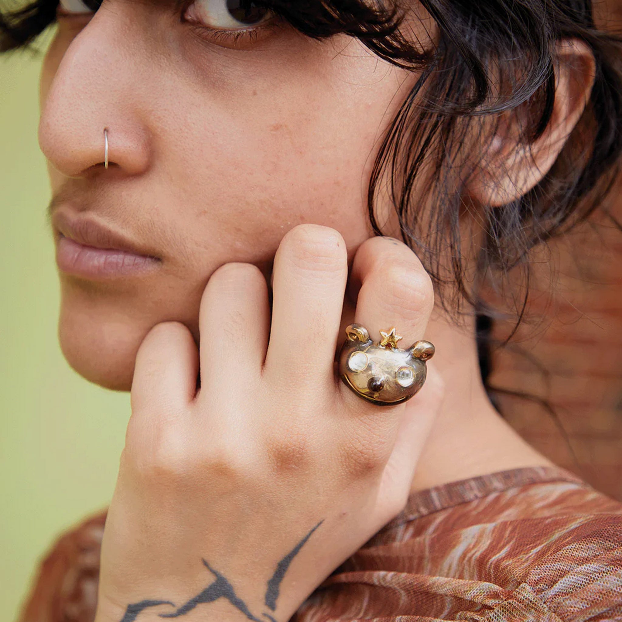 A model wears the Princess Bear Ring in antique gold, a recycled pewter ring shaped like a bear's head wearing a star crown and clear glass eyes.