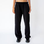 A model wears the Les Tien Puddle Pant in Jet Black, a long, straight-legged sweatpant with extra length that puddles at the feet - front view.