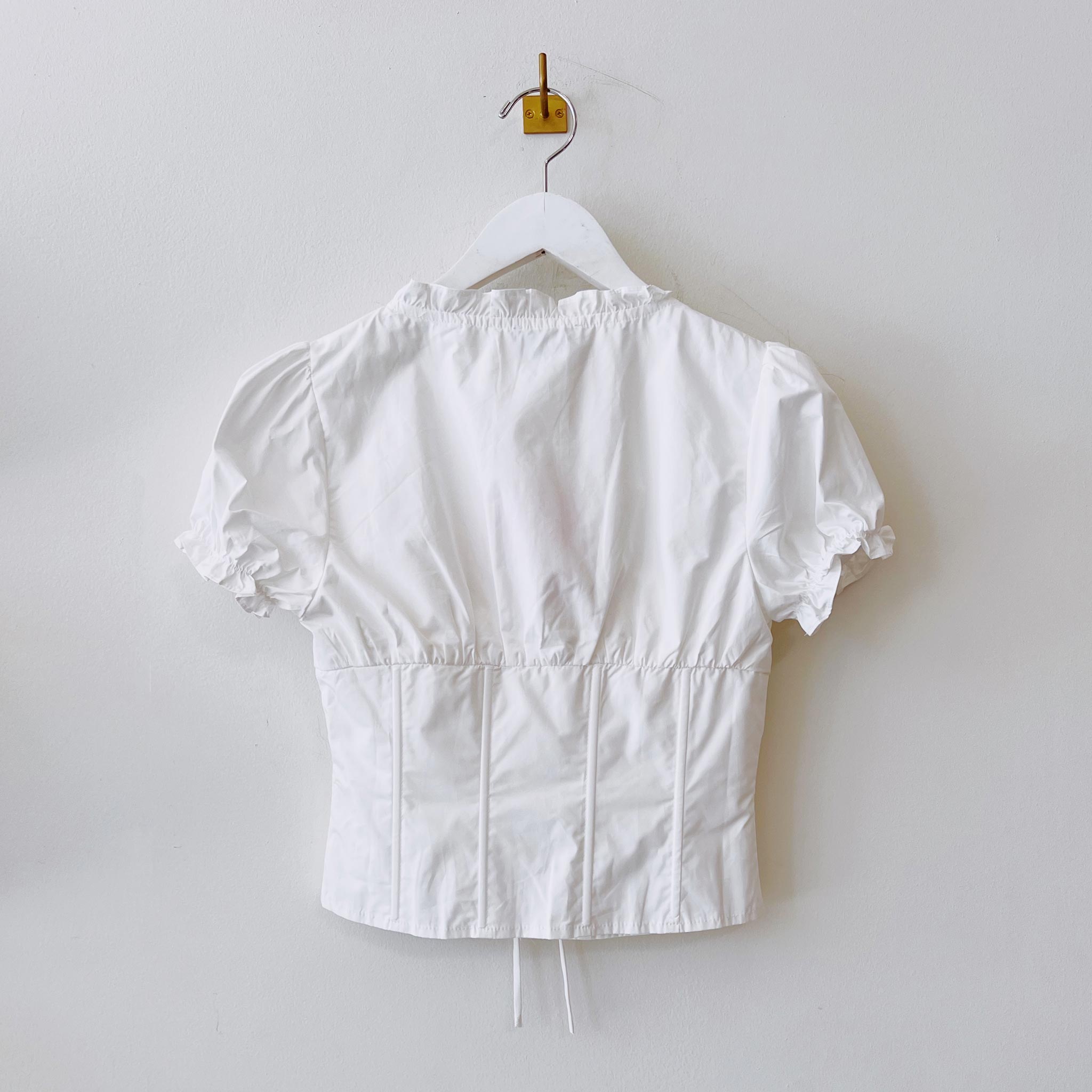 Back hanging photo of the Puff Sleeve V-Neck Top - White.