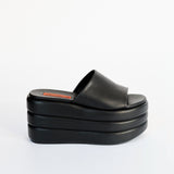 Side view of a black platform slide shoe in vegan leather.