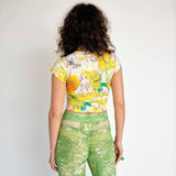 Yellow baby tee with illustrative graphic and white PUPPIES letters printed across the chest over a large heart symbol - back view.