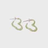 Small heart shaped earrings with silver posts and encrusted with tiny green rhinestones.