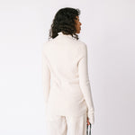 A model wears the white ribbed mock neck by Lauren Manoogian, paired with white pants - back view.