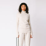 A model wears the white ribbed mock neck by Lauren Manoogian, paired with white pants.